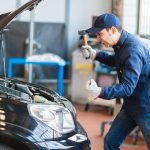 Angry mechanic smashing a car engine